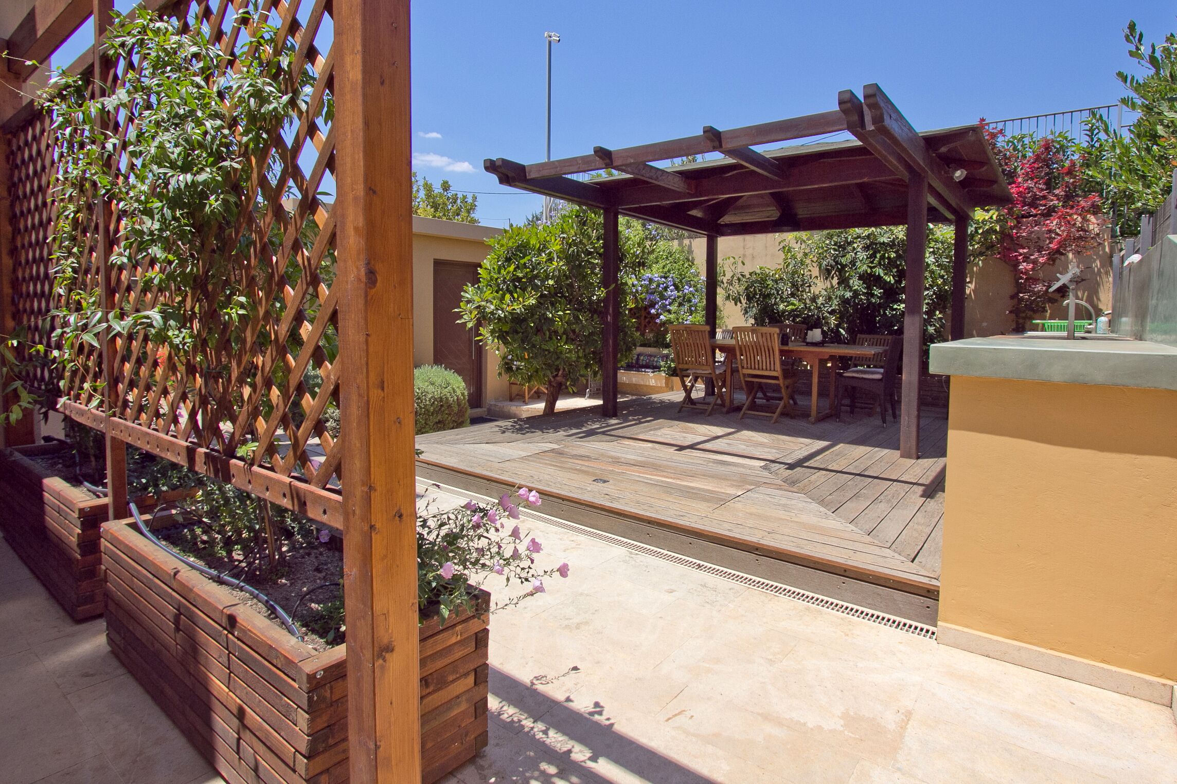 A covered patio area with wooden furniture and a pergola.