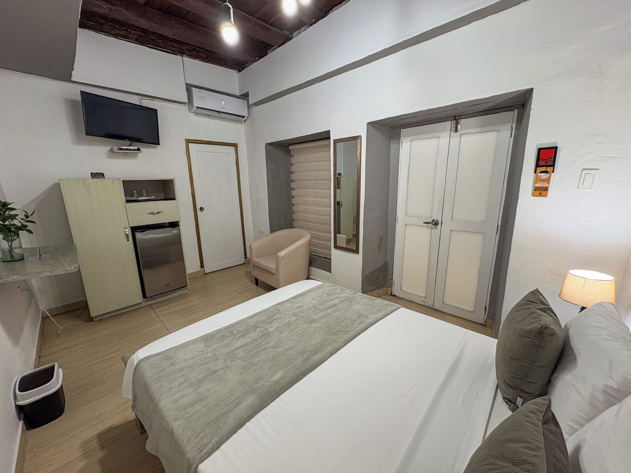 Une chambre d’hôtel comprenant un lit, un bureau avec une télévision, une chaise et une armoire.