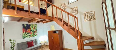 Un intérieur en bois à plusieurs niveaux, comprenant un escalier, un canapé, un meuble et un tableau.