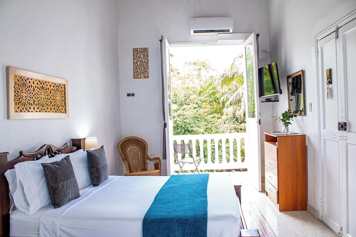 Un dormitorio con cama, una silla, televisor y armario.