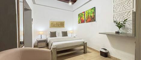 Un dormitorio moderno con cama, mesitas de noche, una silla y obras de arte en las paredes.