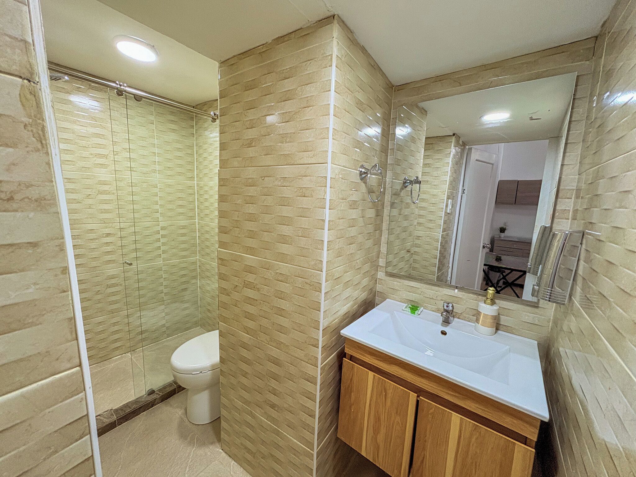 A bathroom with a shower, toilet, sink, and mirror.