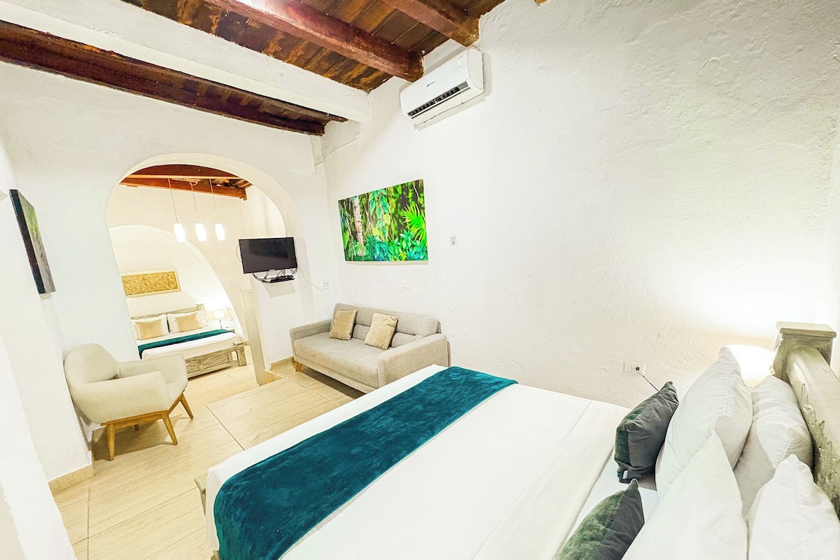 Una habitación con una cama grande, un sofá, un televisor y un cuadro en la pared.