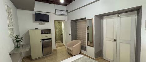 A bedroom with a bed, a desk, a chair, a wardrobe, and a television.