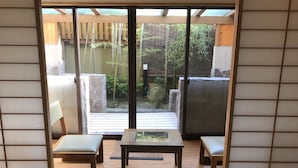 A traditional Japanese room with tatami flooring, a low table, and two cushioned seating areas. - Ritouen (Ureshino)