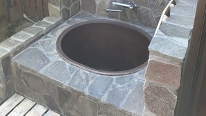 A stone hot tub with a stone wall and a wooden fence in the background. - Ritouen (Ureshino)