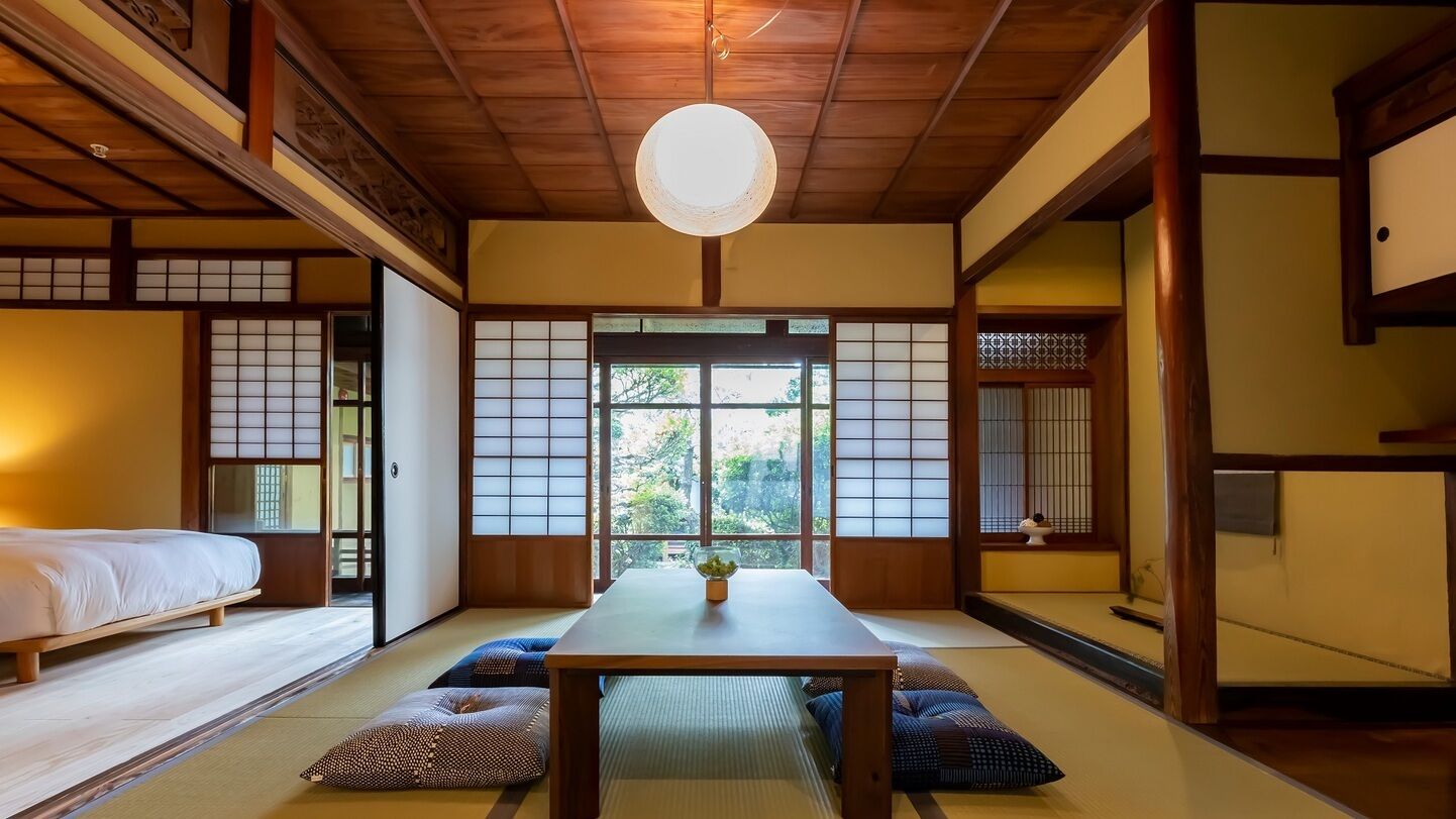 Una habitación tradicional japonesa con suelo de tatami, una mesa baja y puertas correderas.