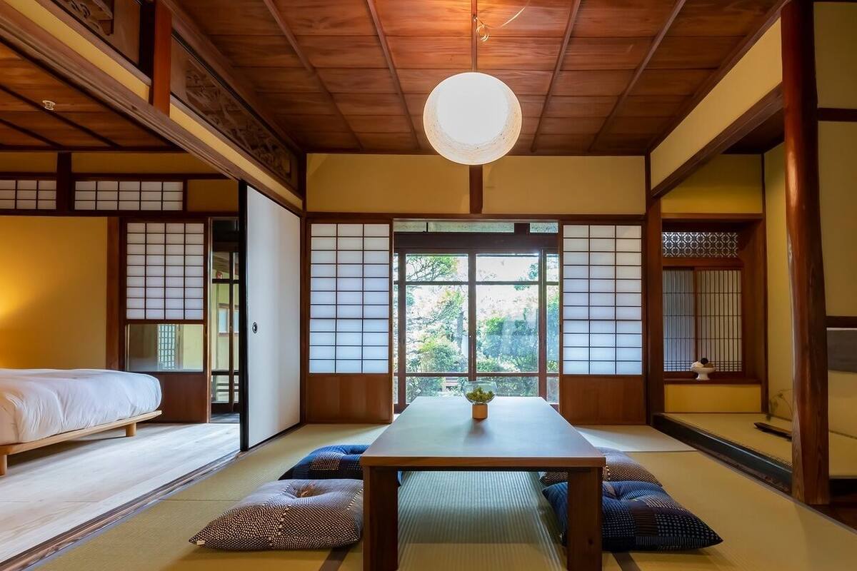 Una habitación tradicional japonesa con suelo de tatami, una mesa baja y puertas correderas.