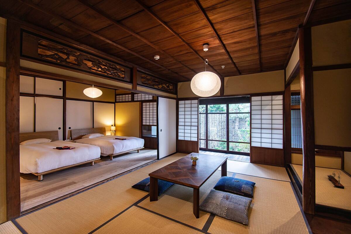 Una habitación tradicional japonesa con suelo de tatami, una mesa de madera baja y dos esteras de tatami con cojines.