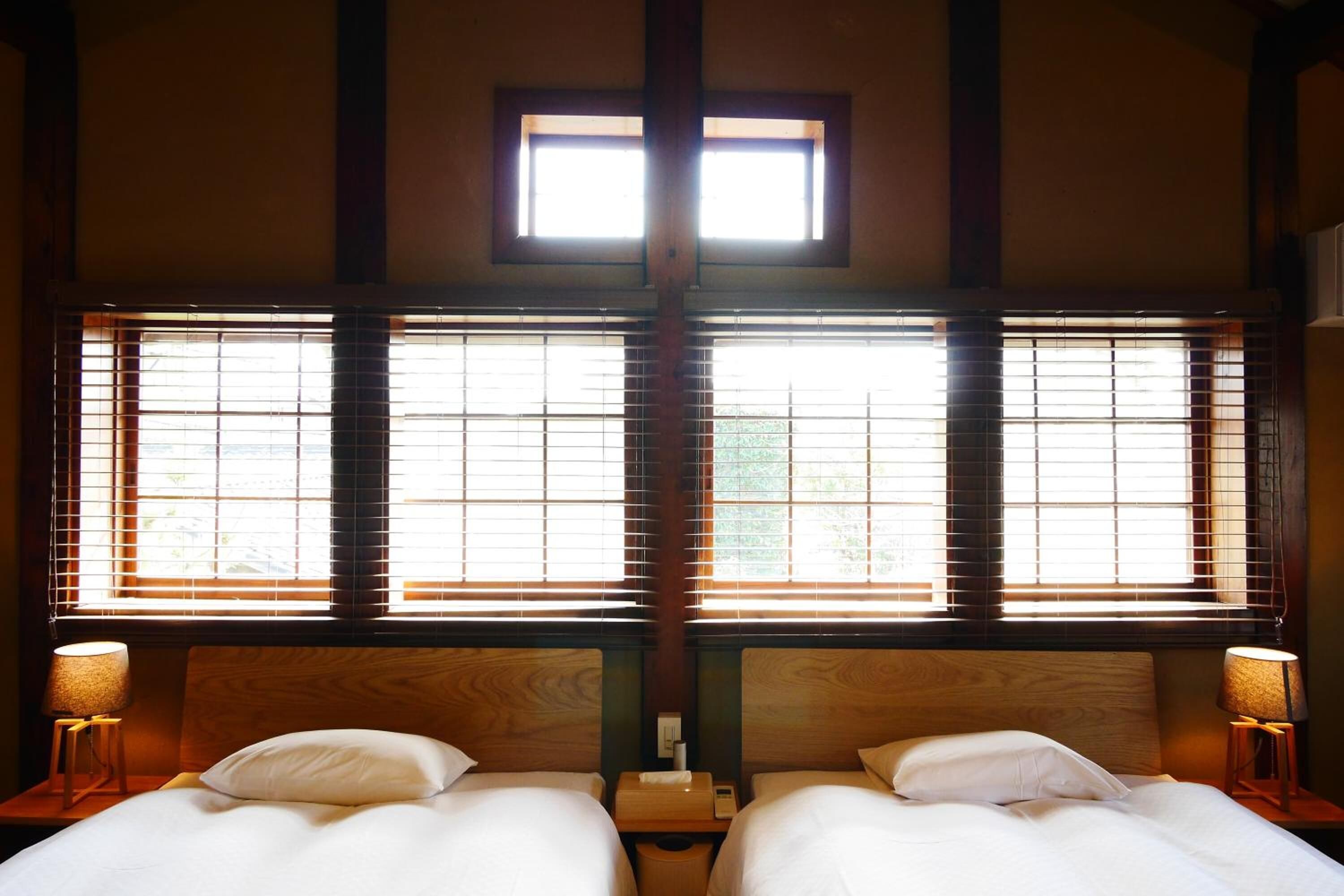 A room with two beds, wooden headboards, and a window with blinds.