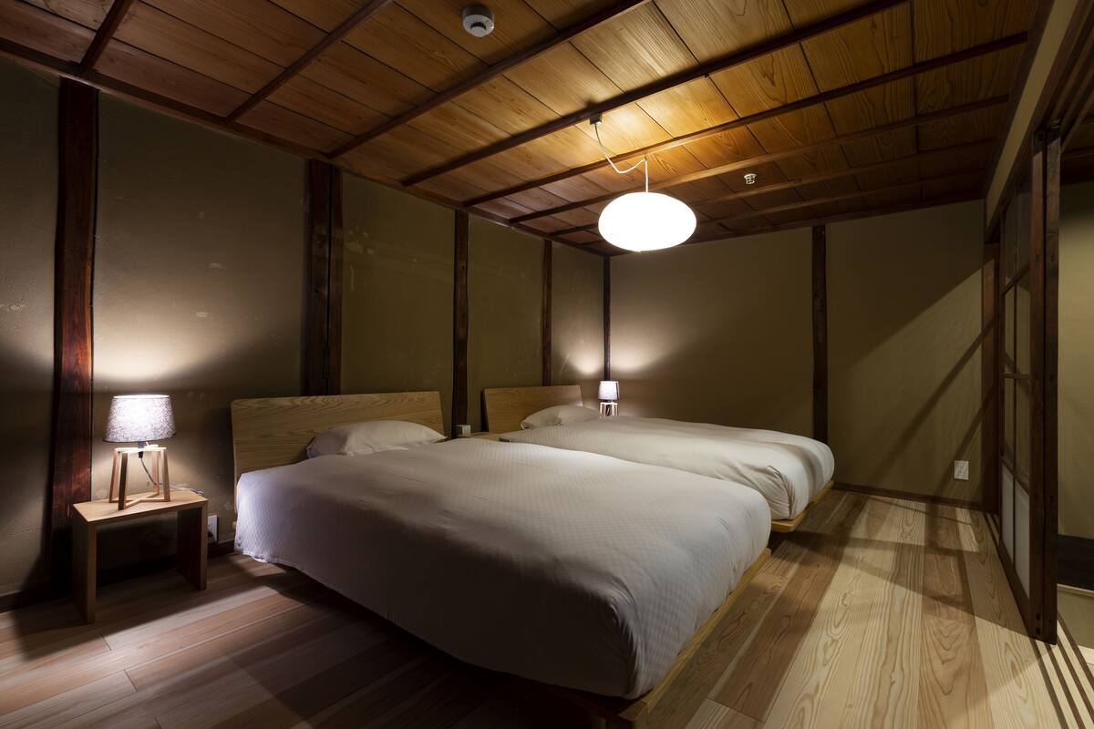 Un dormitorio con dos camas, suelo de madera y techo inclinado con vigas a la vista.