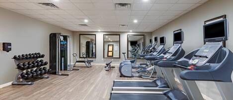 A gym with treadmills, dumbbells, and exercise equipment.