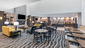 A hotel lobby with a fireplace, seating areas, and a bar.