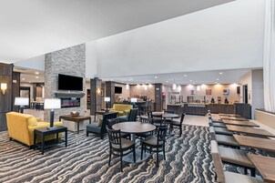 Un vestíbulo de hotel con chimenea, zonas de estar y un bar.