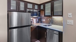 Een compacte keuken met roestvrijstalen apparatuur, donkere houten kastjes en een modern design.
