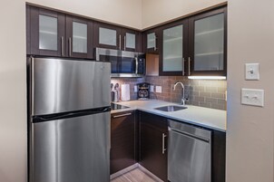 Una cocina compacta con electrodomésticos de acero inoxidable, armarios de madera oscura y un diseño moderno.