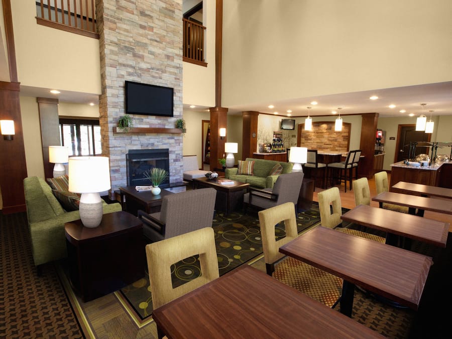 A hotel lobby with a fireplace, seating area, and a bar.