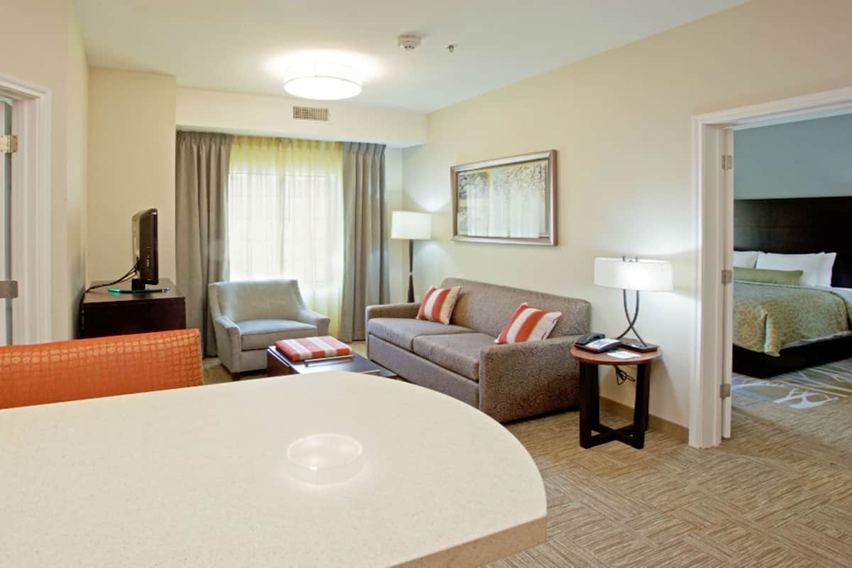 Een hotelkamer met een bed, een bank, een stoel, een bureau en een eettafel.