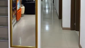 A hallway with a mirrored wall, a vending machine, a clock, and a leather couch. - Kleinn Hotel Bogotá (Bogotá)