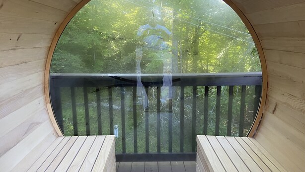 A wooden deck with a circular window, offering a view of a forested area. - Enjoy private...beautiful… large house with outdoor hot tub and sauna ! (Slaty Fork)