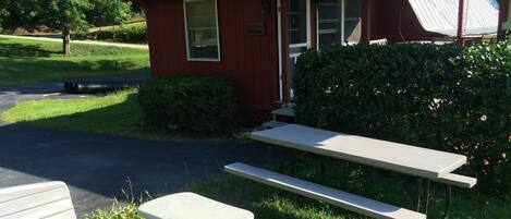 A red building with a large 'U' on the roof, a picnic table, and a bench.