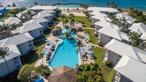 Un resort con piscina central, varias habitaciones de huéspedes y vistas al océano.