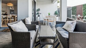 A modern outdoor patio with wicker furniture, a dining area, and potted plants.