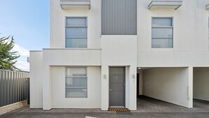 A modern building with a flat roof, large windows, and a central door.
