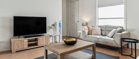 A modern living room with a flat-screen TV, wooden coffee table, and a sofa.