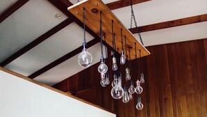 Ein geräumiger Raum mit einer Holztreppe, einem Essbereich mit Tisch und Stühlen sowie einer Hängeleuchte mit mehreren Lampen.
