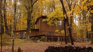 Eine Holzhütte im Wald mit einer Terrasse und einem kleinen Anbau.
