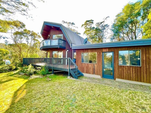 Una casa moderna con fachada de madera, un balcón y una antena parabólica.