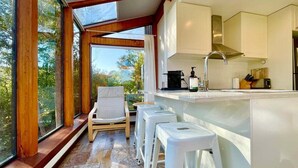 A modern kitchen with a bar area, large windows, and a view of the outdoors.