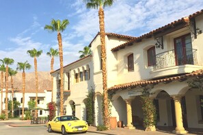 Un coche amarillo estacionado frente a un edificio con un letrero que dice 'JARAH JADE'.