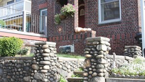 A brick building with a stone wall in front, a balcony, and a hanging flower basket. - Historic Brick Mission House close to everything (Seattle)