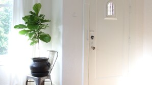 A room with a potted plant, a chair, a patterned rug, and a white door with a small window. - Historic Brick Mission House close to everything (Seattle)