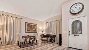 Un comedor con una mesa, sillas y un piano.