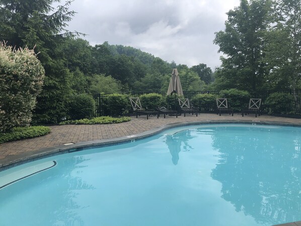A swimming pool with a curved edge, surrounded by a brick patio, and shaded by a canopy. - Four Seasons Private Suite on Chestnut Ridge in Highlands - Private Club Access (Highlands)