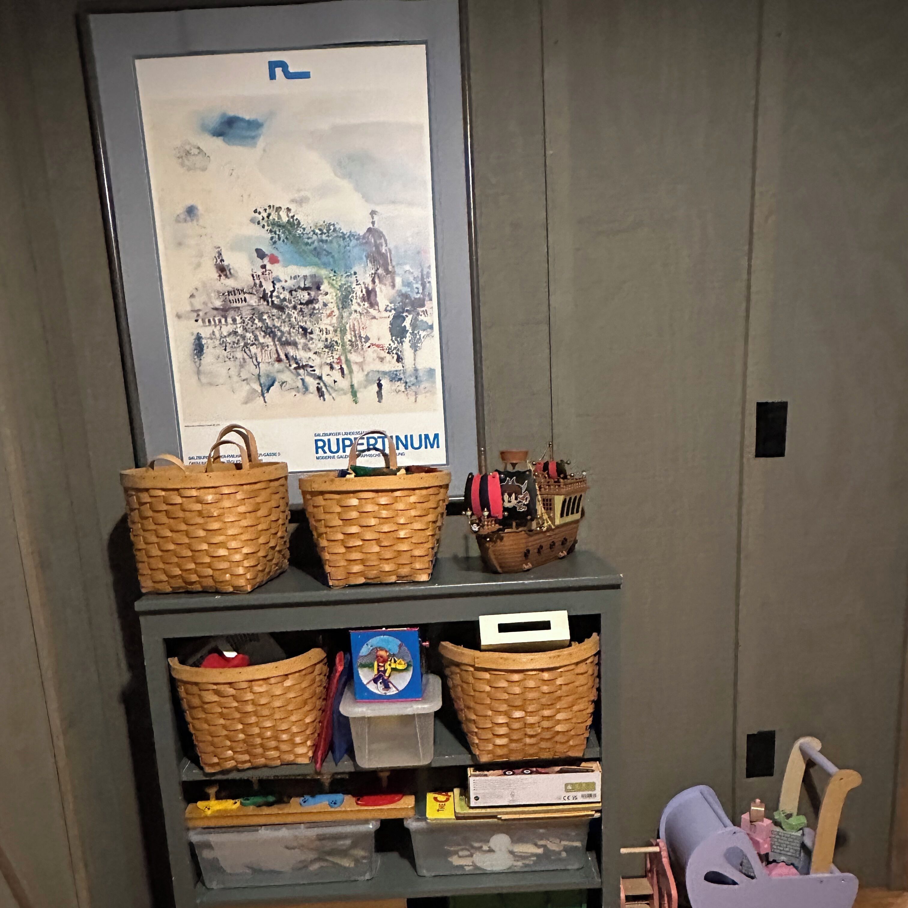 A shelf with woven baskets, a framed picture, and a small ship model.
