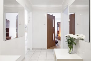 Enter a serene bedroom with a comfortable bed, a wooden door, and a stylish mirror.