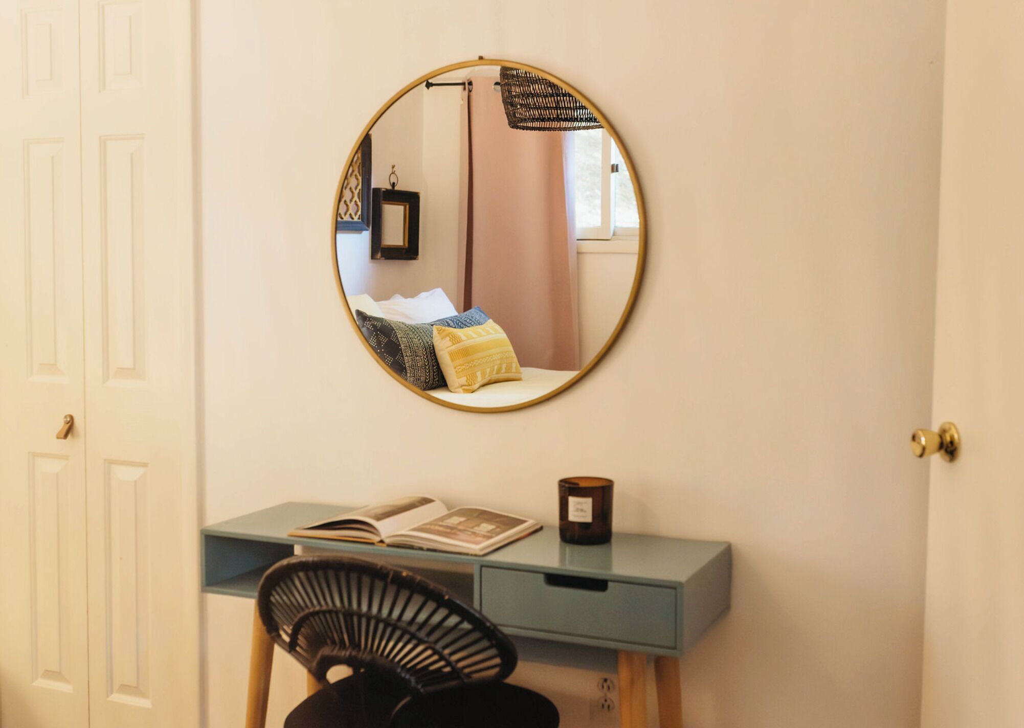 Een kamer met een bureau, stoel en een ronde spiegel aan de muur.