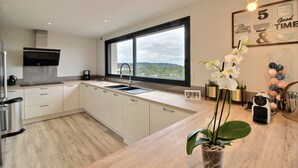 Eine moderne Küche mit einem großen Fenster, weißen Schränken und einer Holz Arbeitsplatte.