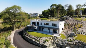 Ein modernes, zweistöckiges Haus mit Flachdach, großen Fenstern und einer Steinmauer.