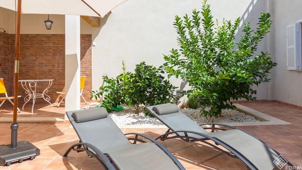 A patio with two lounge chairs, a table, and an umbrella.