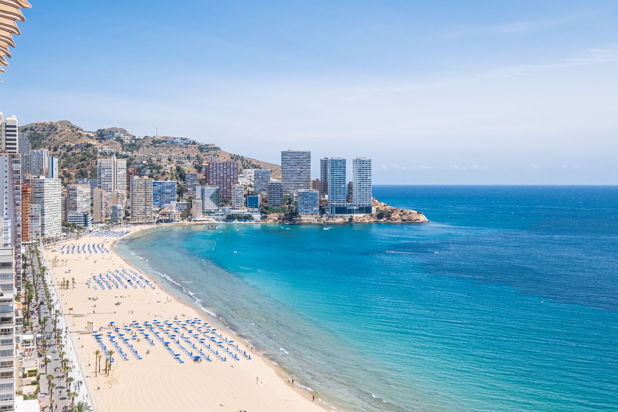 Un paisaje urbano costero con playa, rascacielos y mar azul y despejado.