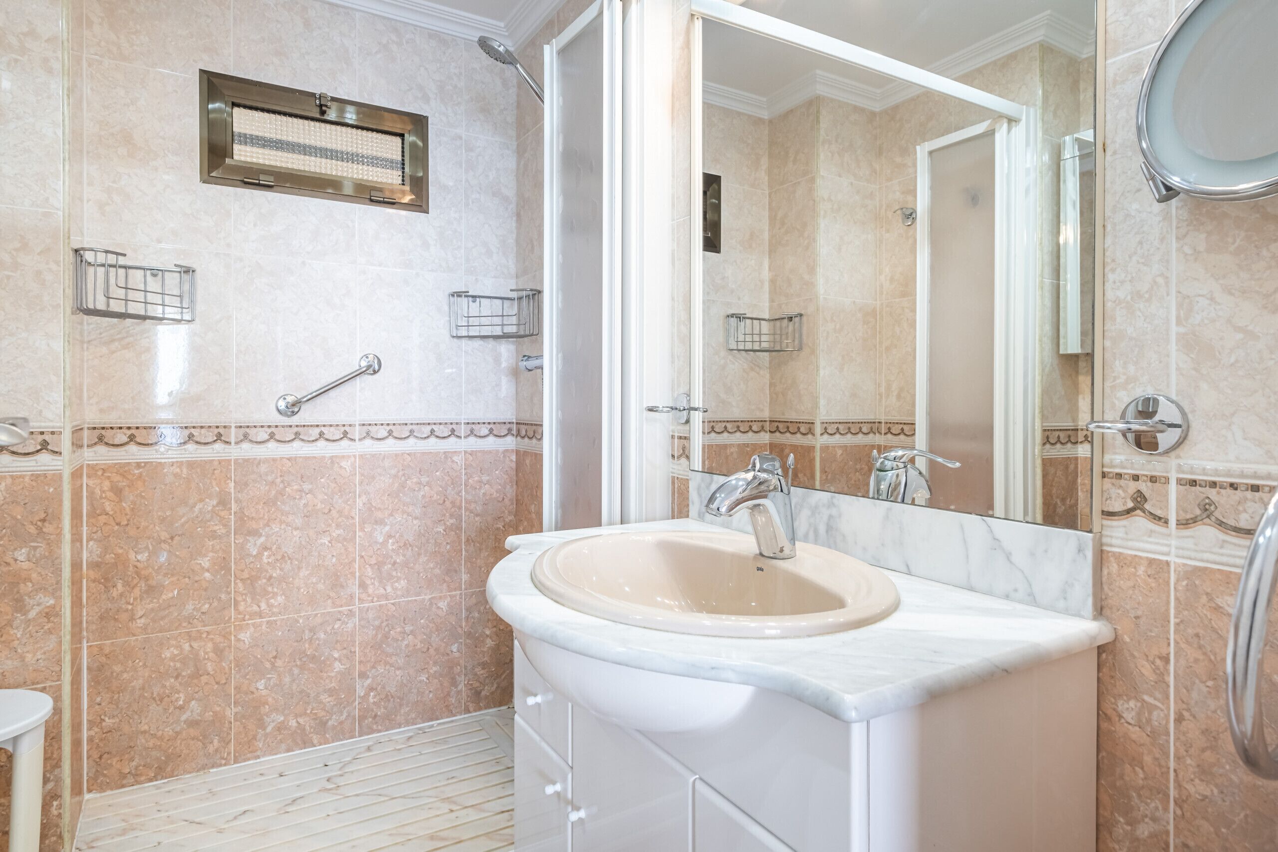 Ein Badezimmer mit Waschbecken, Spiegel, Dusche und Handtuchhalter.
