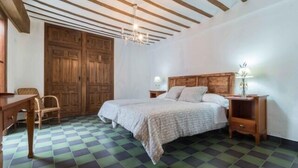Een slaapkamer met een geruit vloerkleed, een houten bedframe en een grote kledingkast.
