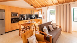 Une cuisine moderne avec des meubles en bois, un coin repas avec une table et des chaises, et un salon confortable avec un canapé et des coussins.