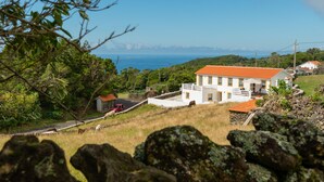 Un bâtiment blanc avec un toit rouge, entouré de verdure et offrant une vue sur la mer.