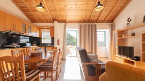 Un intérieur en bois comprenant un coin repas, un canapé et un téléviseur.